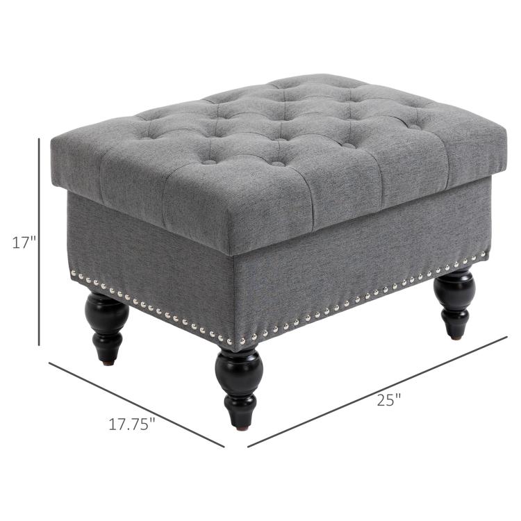 Gray storage ottoman bench with button-tufted top, studded trim, and 25 in length