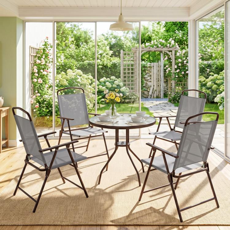 Indoor patio dining set with umbrella, round glass table, and four gray folding chairs