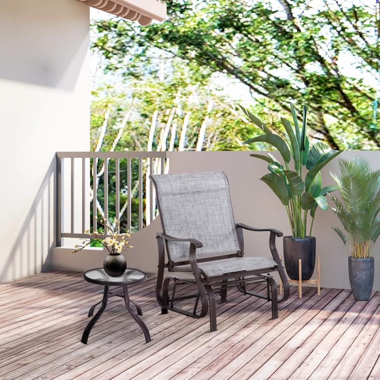 Gray outdoor glider chair on patio with tall backrest and mesh seat