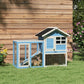 Light blue rabbit hutch with ramp inside, wire enclosure, black roof on grass