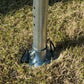 Metal tent support pole secured with ground stake in grass