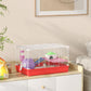 Red hamster cage with white wire top and side panels, green house, and purple wheel stand