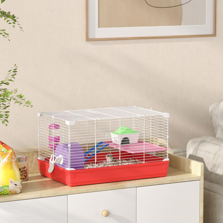 Red hamster cage with white wire top and side panels, green house, and purple wheel stand