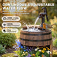 Rustic wooden barrel water fountain with black pump spraying water over blooming flowers