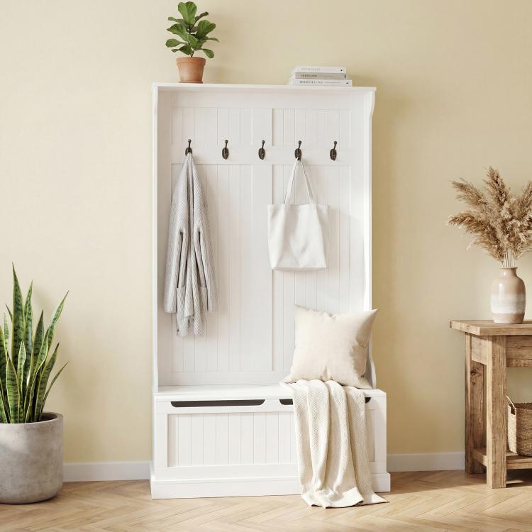 White hall tree bench with coat hooks and shoe storage, hanging coats and pillows