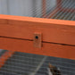 Wooden rabbit hutch corner with black latch/lock on mesh panel frame