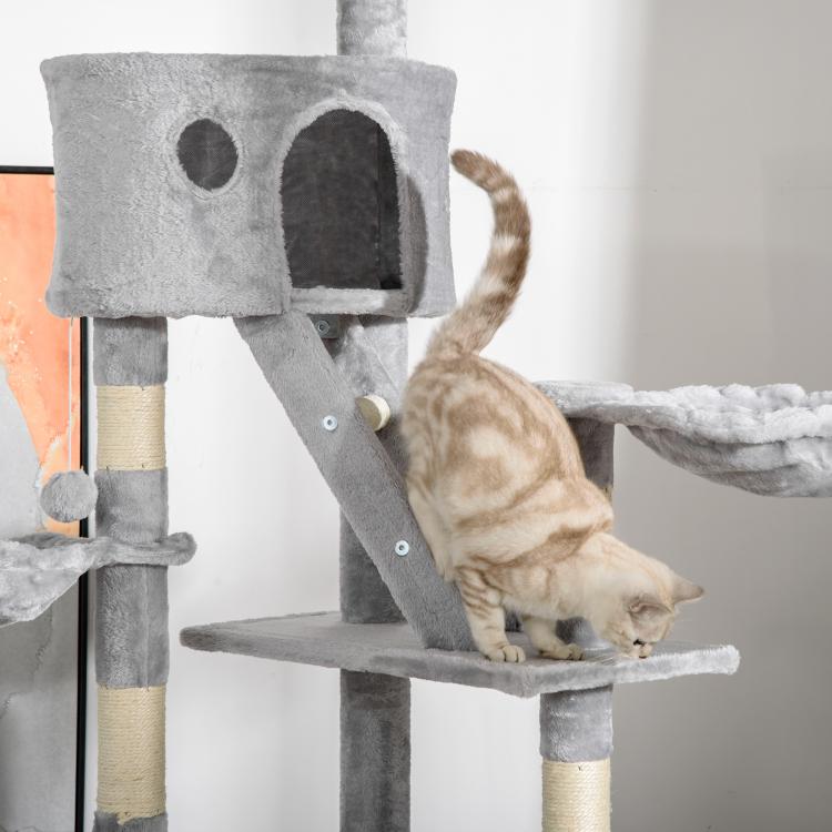 Gray cat climbing tower with condos, rope scratching post, and perches; cat in lower house