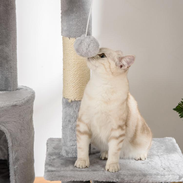 White and cream cat sitting on grey plush base platform of cat tree tower