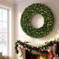 Green pre-lit artificial wreath with dense pine needles and warm yellow LED lights