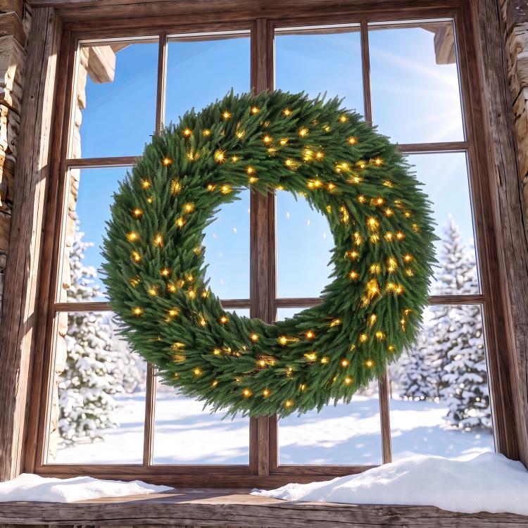 Green pine wreath with warm white LED lights, hanging in a window frame