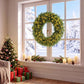 Green pre-lit artificial wreath with warm LED lights, circular evergreen ring by window