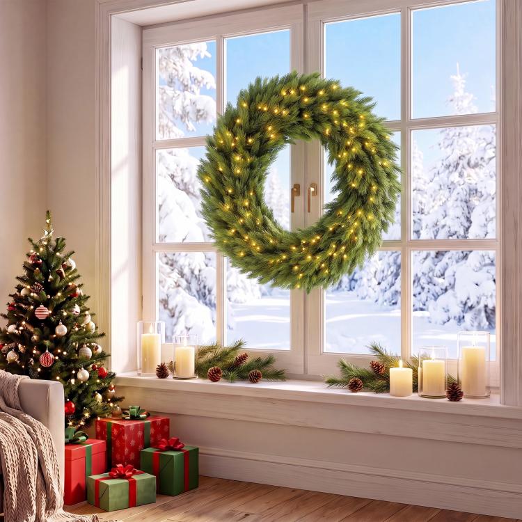 Green pre-lit artificial wreath with warm LED lights, circular evergreen ring by window
