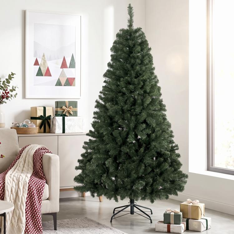 Artificial green Christmas tree with dense branches on metal stand