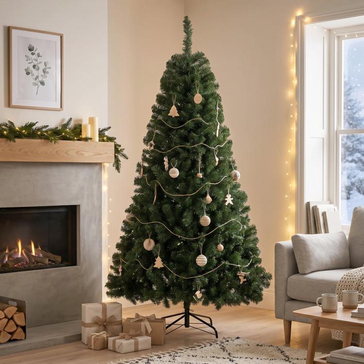 Decorated artificial green Christmas tree with ornaments and string lights on metal stand