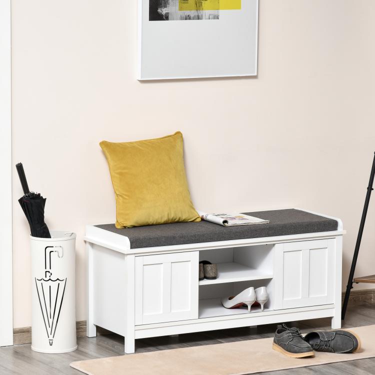 White shoe storage bench with gray cushioned seat and open compartments for shoes