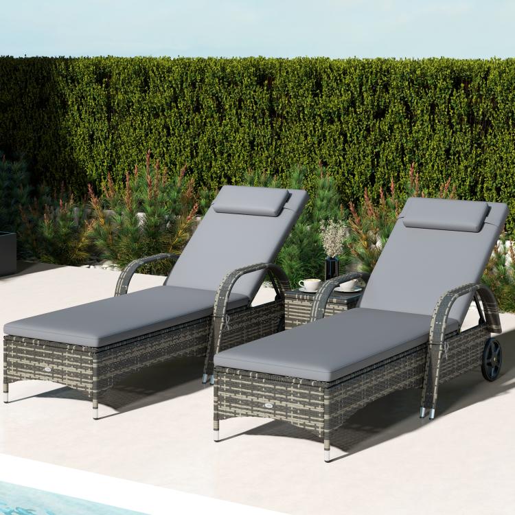 Outdoor chaise lounge chairs with gray cushions and dark wicker armrests, reclined