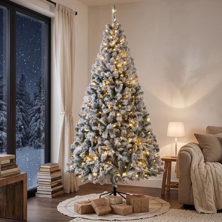 Snow-flocked prelit Christmas tree with dense layered branches and warm string lights.