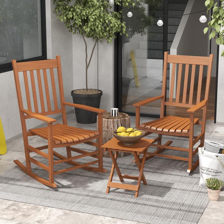 Two wooden rocking patio chairs with slatted seats and backrests, with side table