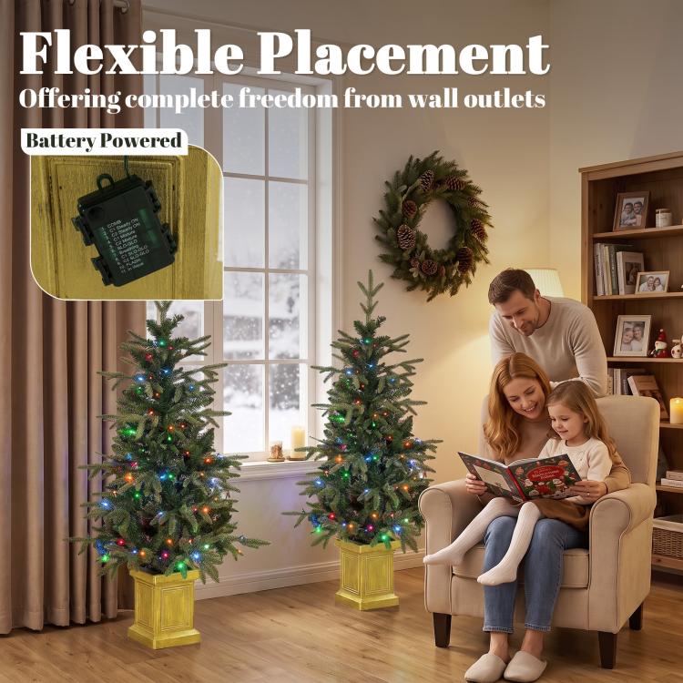 Two battery-powered prelit Christmas trees with glowing lights on square golden bases.