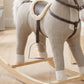 Gray plush rocking horse toy with brown saddle and harness, angled side view