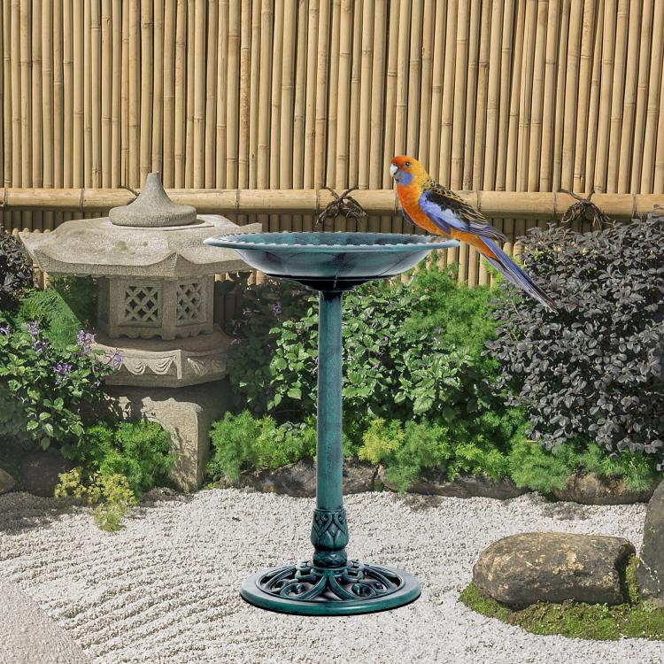 Outdoor bird bath pedestal with teal bowl; colorful bird perched on rim
