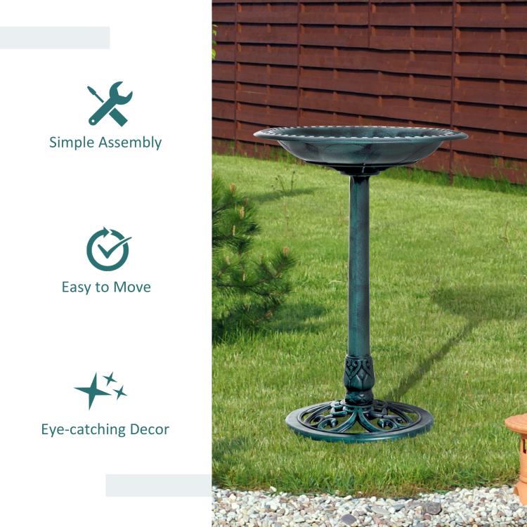 Teal-green outdoor bird bath with ornate base standing on yard
