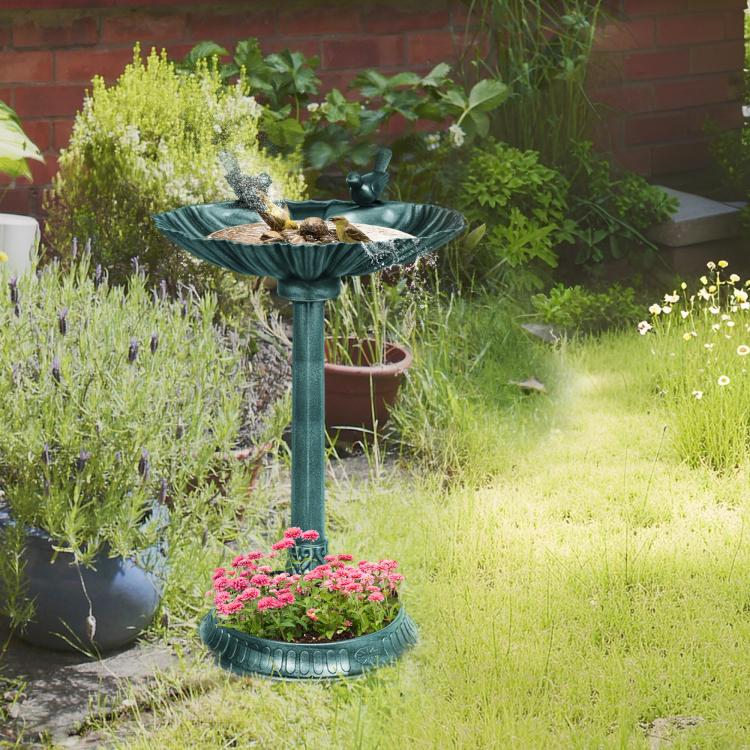 Verdigris bird bath and planter pedestal holding flowers in outdoor garden landscaping