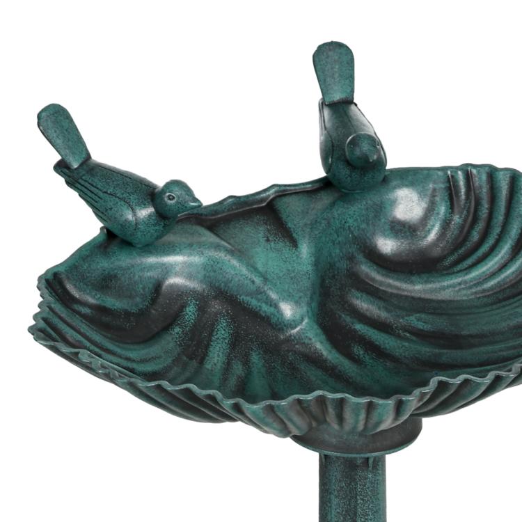 Close-up of verdigris bird bath basin with two bird figurines and shell details