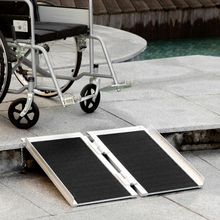 Aluminum folding wheelchair ramp with black anti-slip deck on concrete steps
