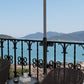 Black umbrella holder stand mounted to railing post with clamp plates