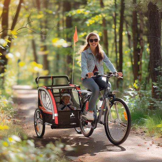 Red and black 2-seat bike trailer pulled on a bicycle with two children inside