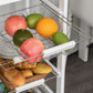 White rolling kitchen cart with wire fruit baskets and drawer; fruit in top basket.