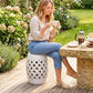 White ceramic garden stool with woven lattice cutouts and perforated top, used as a seat.