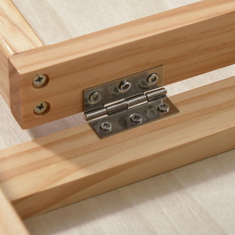 Close-up of metal hinge hardware on a light pine pet ramp support