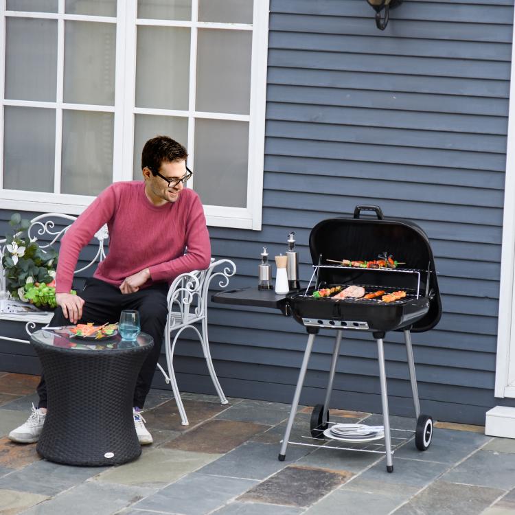 Charcoal barbecue grill with open lid, side shelf, and cooking grate on stand