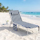 Blue-and-white striped folding tanning chaise lounge chair with side table on sand