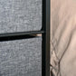Gray fabric drawer front with black steel frame edge on a drawer chest dresser