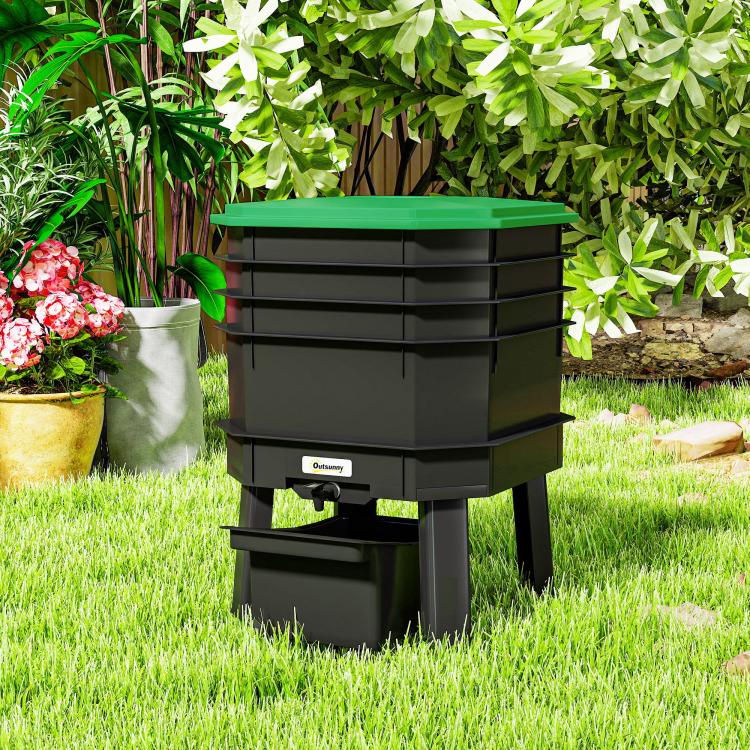 Dark green worm composter bin with open drawer under stacked trays in outdoor garden