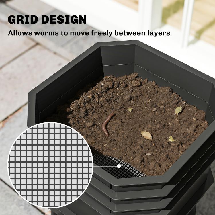 Worm composter tray filled with dark compost soil and a visible worm near mesh insert