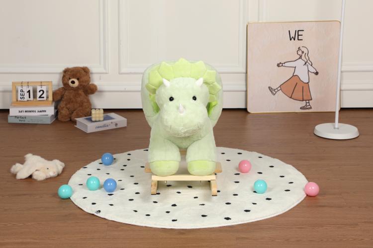 Green plush dinosaur rocking horse with wooden base on a dotted play mat