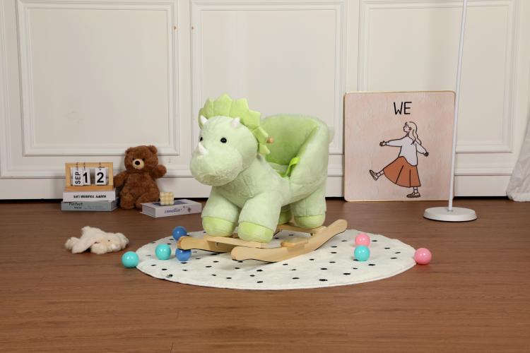 Green plush dinosaur rocking horse front view on a round dotted mat