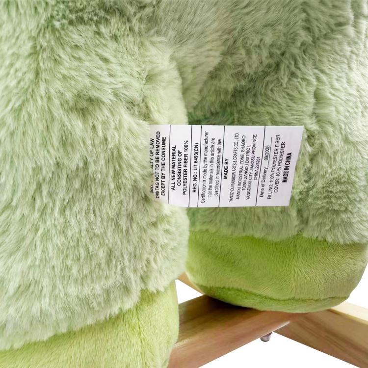 Green plush dinosaur rocker with rectangular care label on side