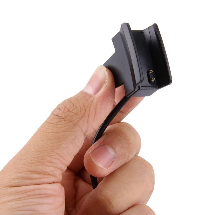 Black charging clip dock with metal pins, handheld view of reset button cable