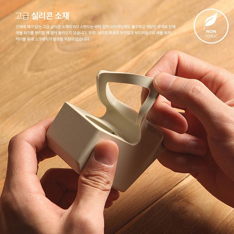 Light gray Apple Watch charging dock stand being inserted, hands adjusting the cradle