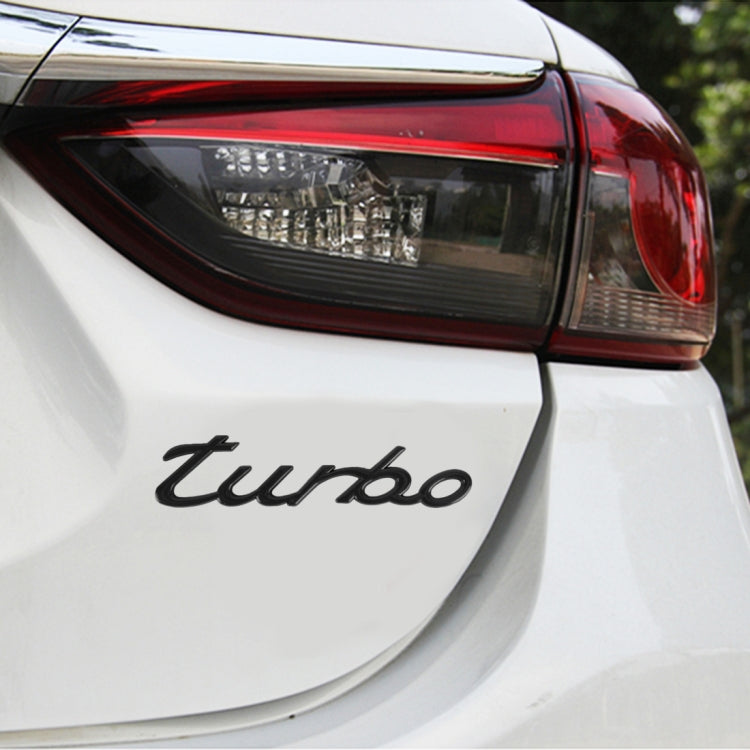 Black "turbo" decorative car sticker, applied on rear panel of a white car