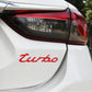 Red "turbo" decorative car sticker applied on rear panel of a white car