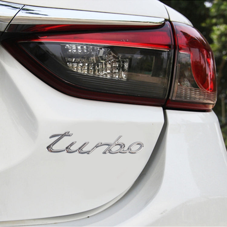 Silver "turbo" decorative car sticker applied on rear panel of a white car