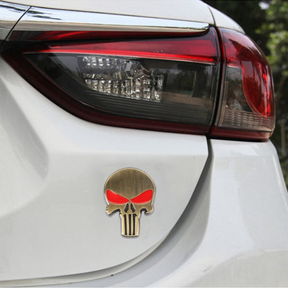 Gold metal skull car sticker with red eyes on round mounting backing