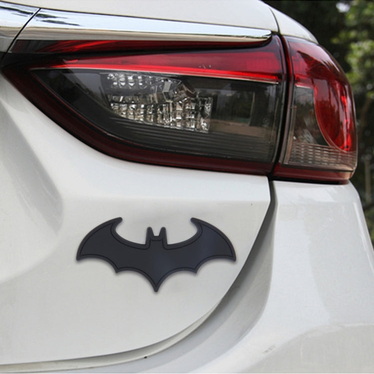 Metal bat car sticker with shiny black bat design on the rear of a white car