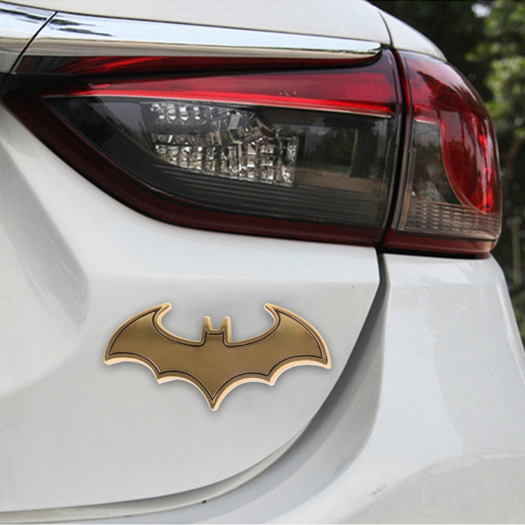 Metal bat car sticker with shiny gold bat design on the rear of a white car